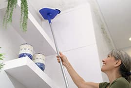 Woman using Wall Wizard™ to reach high corners